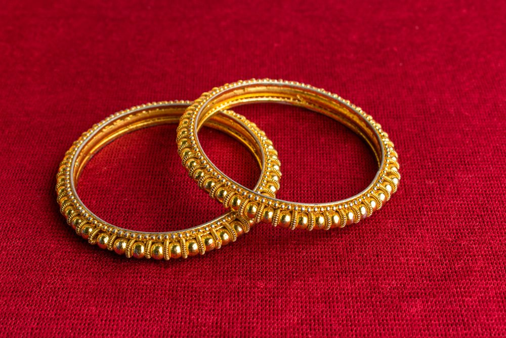 Beautiful shiny golden bangles with Indian traditional design on a red velvet background
