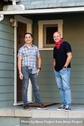Two men standing in front of front door to house smiling and looking at camera 5lVzob