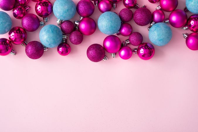 Pink and blue festive baubles on side of pink background