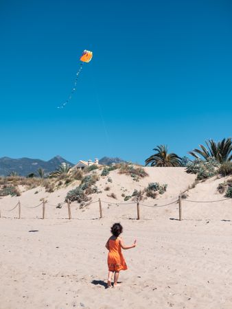 Toddler girl playing with kite on sandy beach