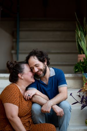 Portrait of loving married couple snuggling close together sitting on stairs
