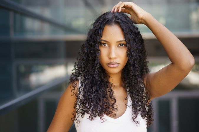 A Confident Young Woman Showcasing Her Curly Hair While Posing Outdoors in Style