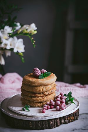 Pile of raspberry pancakes with honey on plate