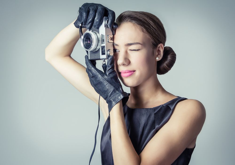 Model in vintage clothing and gloves with camera to her eye