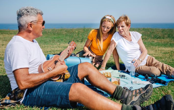 Family on outdoor picnic with ukulele