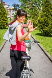 Young sportive woman with bike waving