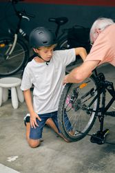 Concentrated boy inflating tire with grandfather