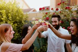 Group of cheerful friends clinking glasses at party