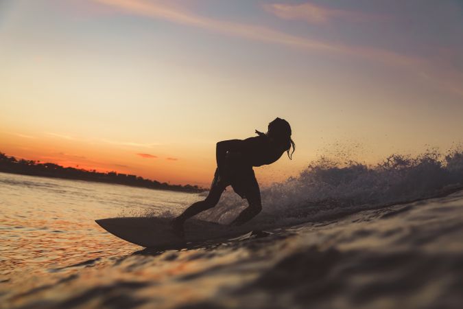 Man on surf board on waving water at sunset