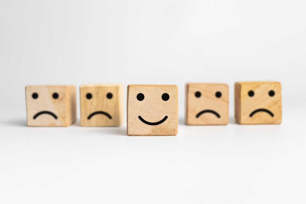 sad faces and happy face expression emoji on wooden block