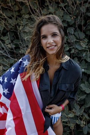 Young woman in casual clothing and American ensign enjoying in nature