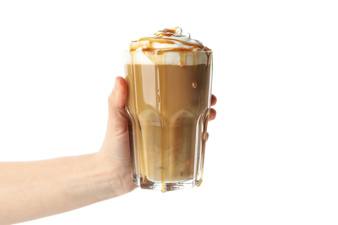 Female hand holds iced coffee with poured cream isolated on plain background