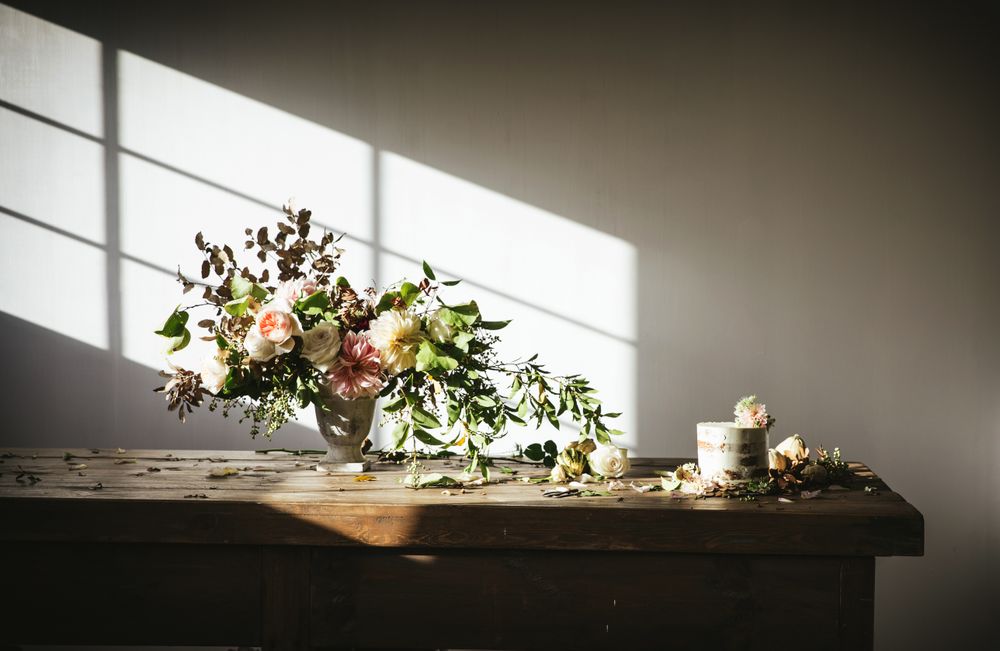 plate with cake decorated flower on table with bouquet of blooms in vase
