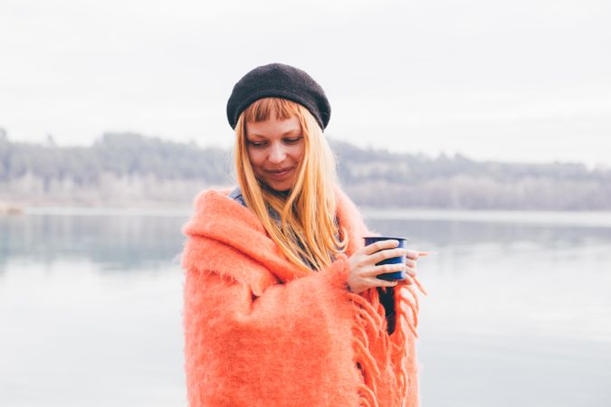 Woman outside in cozy attire with a mug