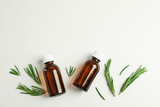 Flat lay composition with rosemary oil and leaves on plain background, space for text
