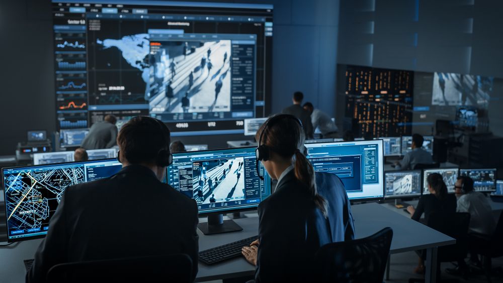 Surveillance Center Monitors Global Activity. Operators Analyze Data on Multiple Screens Showing World Maps, Crowd Movements, and City Layouts.