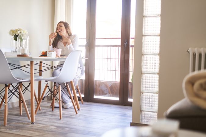 Smiling woman eating at table at home