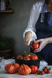 Woman cutting tomatoes in pot at table