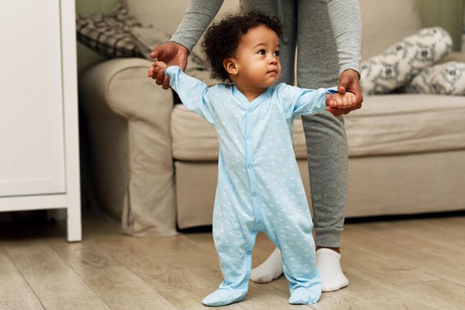 Baby boy taking steps with his mother’s help