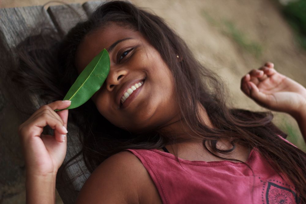 Woman in pink tank top holding green leaf