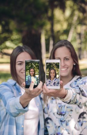 Women showing smartphones with their portraits