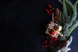 Top view of Christmas present with baubles and surrounded by pine branch