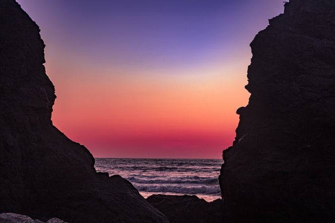 Beautiful dusk seen from behind cliffs of rocky beach