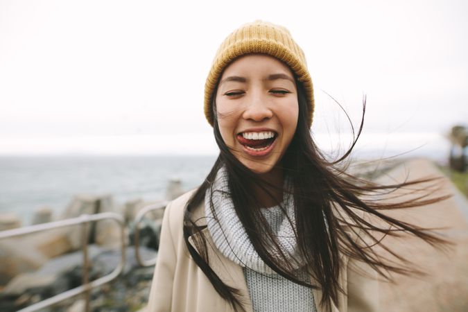 Young woman in winter clothes making silly face with tongue out