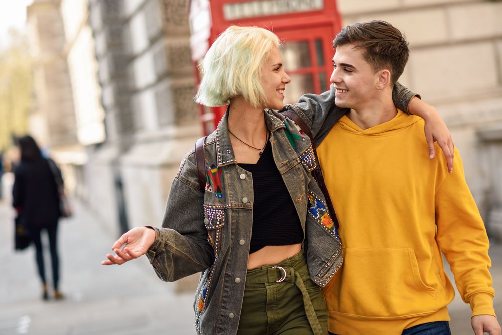 Male and female with arms around each other in front of a phone booth