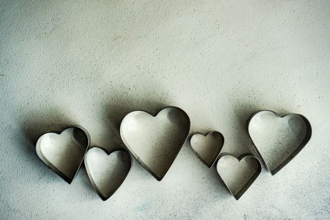 Top view of heart shaped cookie cutters scattered on grey counter