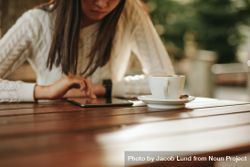 Cropped shot of woman using digital tablet while sitting at table with cup of coffee bG3aBb