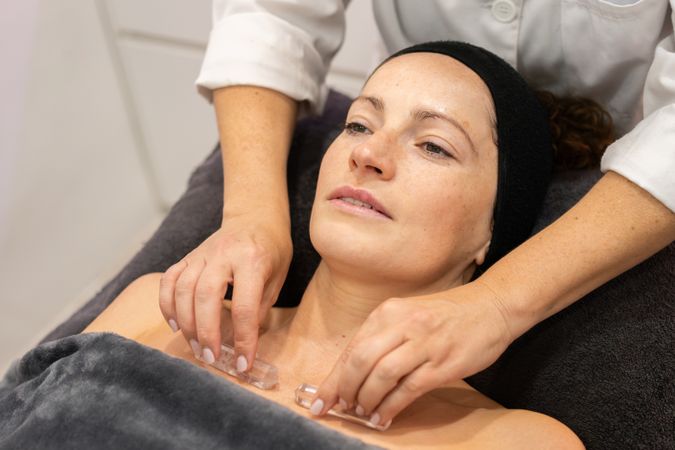Crop of masseuse doing massage to client in salon