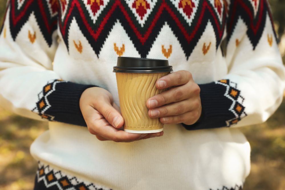 Woman in sweater hold paper cup outdoor