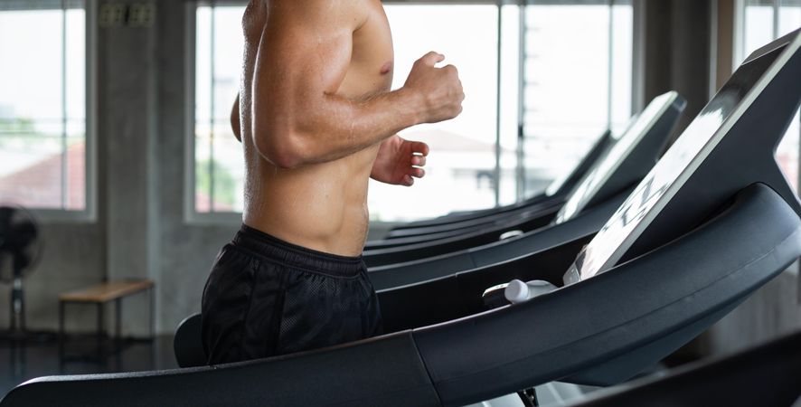 Male torso running on treadmill in gym