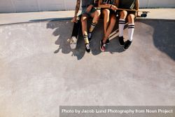 Legs of female skaters sitting together at skate park 0LOGRb