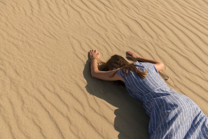 Young woman lying down on sand dune