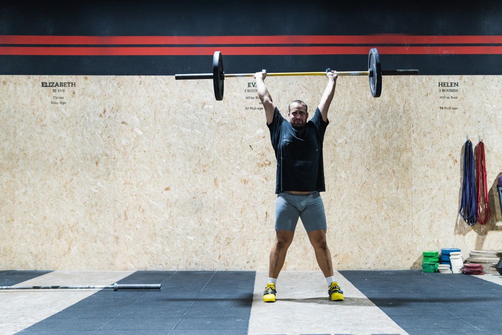 Muscular sportsman lifting heavy barbell