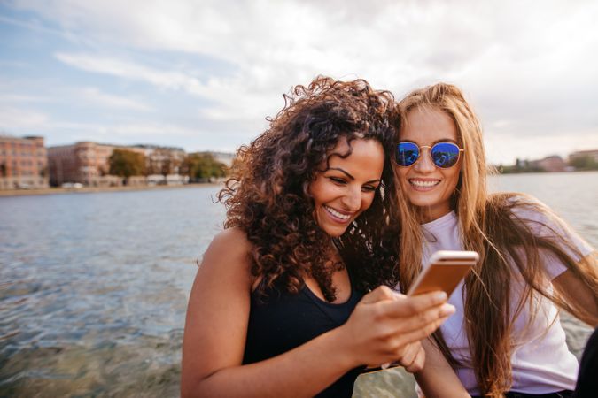 Shot of two young women looking at mobile phone and smiling