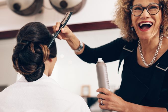 Mature hairdresser laughing and having fun at salon