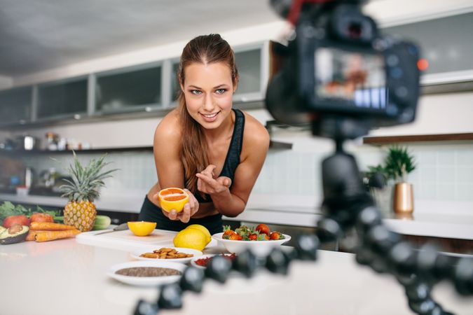 Woman pointing towards a cut lemon facing the camera