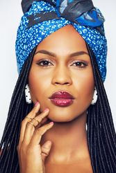 Studio portrait of woman wearing a blue wrap with her hand to her cheek