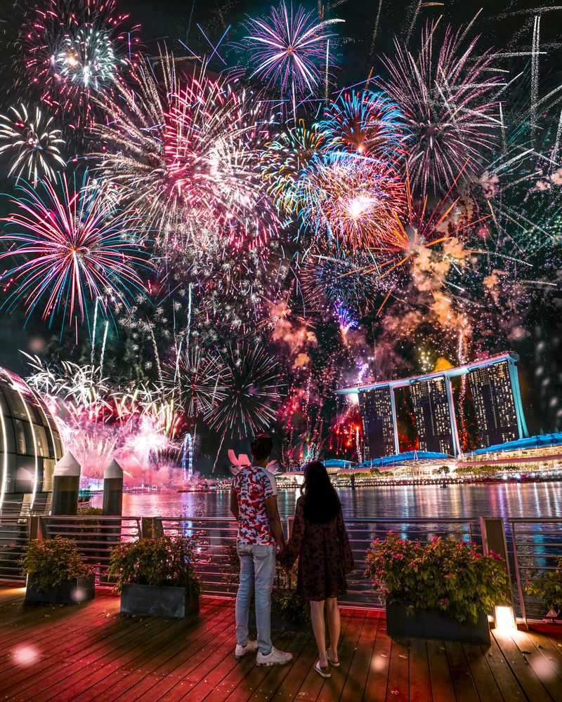 Couple standing at the harbor watching fireworks display