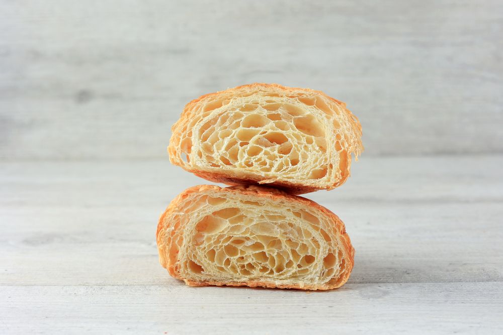 Cut in Half Croissant with Inside Texture and Thin Crisp Layers on Wooden Table.