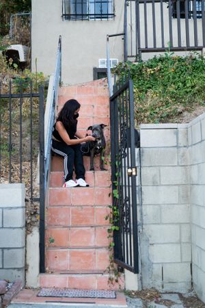 Woman and her dog sitting on stairs in front of house preparing for dog walk