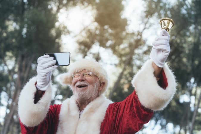 Happy Santa Claus with smartphone and bell