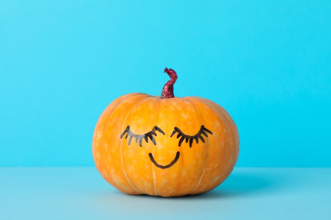 Pumpkin with smile on blue background, space for text