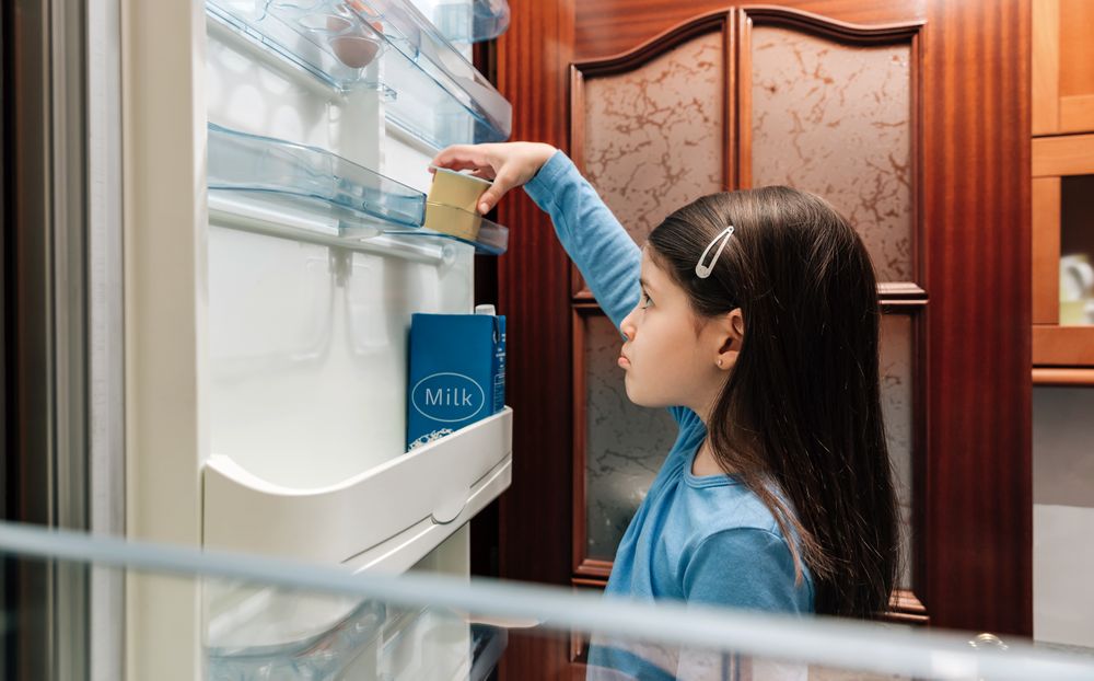Sad girl taking the last yogurt from the fridge