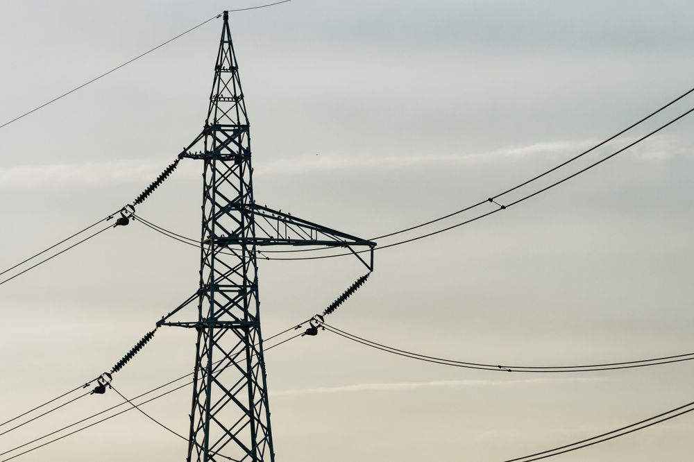 Silhouette of a Powerline Tower Against a Clouded Sunset Sky