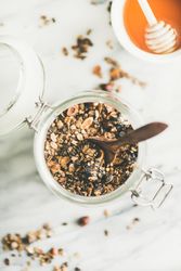 Top view glass container of homemade granola, with honey