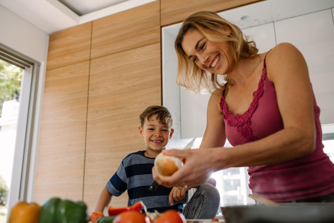 Happy mother and son preparing food in kitchen